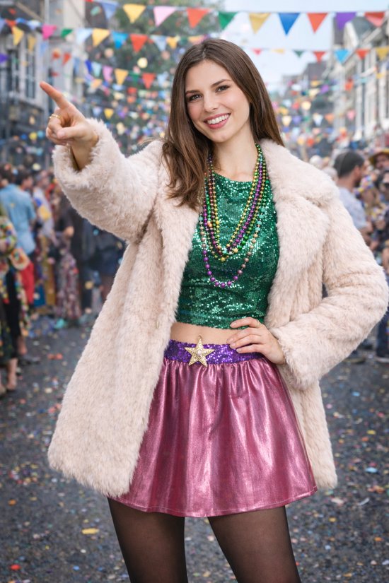 Vrouw op straat draagt een crèmekleurige nepbontjas, glinsterende groene top, paarse rok en kralenkettingen.