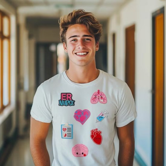 Model met een wit T-shirt versierd met diverse medische strijkapplicaties: ER NURSE, longen, hart, spuit, pleister, hersenen, hart met stethoscoop.