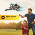 Vader en zoon spelen buiten met een zwarte straaljager drone met blauwe vleugelranden en rode/groene accenten. De drone vliegt, vader wijst.