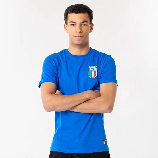 Jongeman met gekruiste armen draagt een blauw T-shirt met op de borst het 'Italia' logo met vier sterren en de Italiaanse vlag.