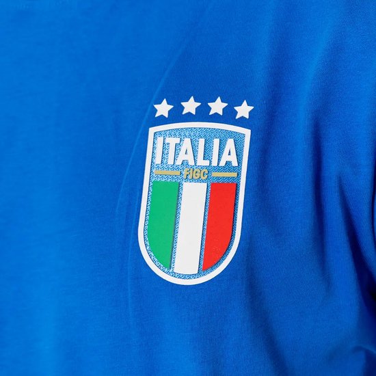 Close-up van het 'Italia' logo op een blauw T-shirt. Het logo bevat vier sterren en de Italiaanse vlag met de tekst 'FIGC'.