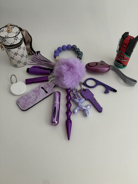 Paarse zelfverdedigingsset met sleutelhanger, spuitbus, pompon, lipstick-achtige objecten en een mini-portemonnee.