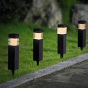 Rij van vier zwarte, vierkante tuinlampen met warm wit licht, geplaatst langs een gazon en stoep.