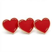 Drie rode hart broches met goudkleurige rand op een witte achtergrond.