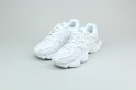 Paar witte New Balance 9060 sneakers op een grijze achtergrond.