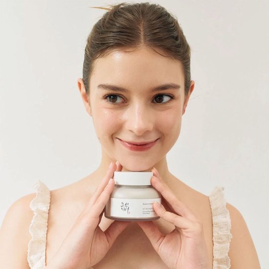 Model met de 'Ground Rice and Honey Glow Mask' van Beauty of Joseon, met glanzende huid en glimlach.