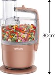 Rosekleurige Kenwood keukenmachine gevuld met gesneden groenten.