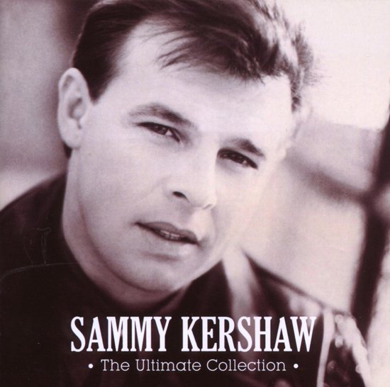 Close-up van Sammy Kershaw, met donker haar en een donkere blouse.