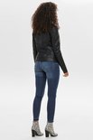 Achterkant van model met krullend haar in zwart kunstleren jack en jeans.