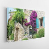 Canvas schilderij - Vibrant green ivy and purple flowers grow over a medieval stone building in France.-     1406601515 - 115*75 Horizontal