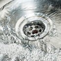 Water stroomt door een gootsteenafvoer met luchtbellen.