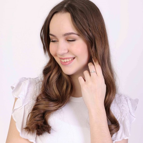 Jongedame met bruin haar draagt een zilverkleurige ring met zirkonia.