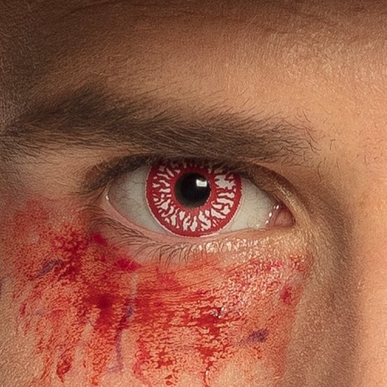 Close-up van een oog met rode contactlens en realistische bloedvlekken onder het oog.