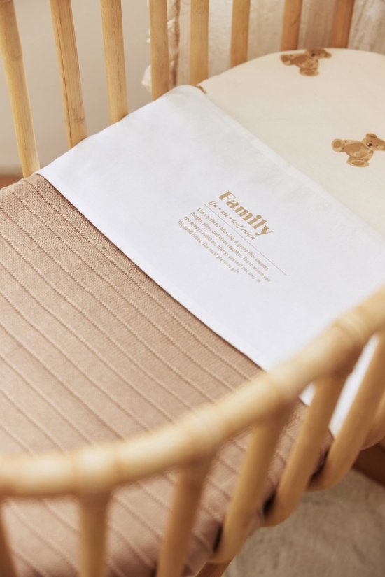 Couverture blanche avec le texte doré 'Family' et une couverture tricotée beige en dessous.