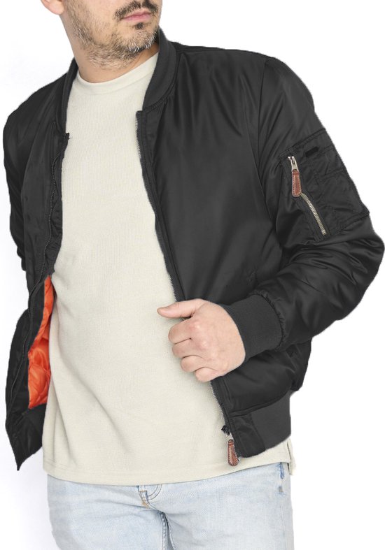 Man met zwarte bomberjack en oranje voering, open rits, lichtbeige shirt en spijkerbroek.