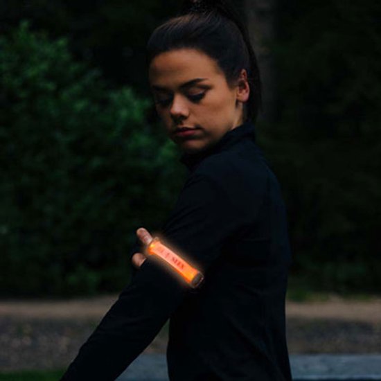 Vrouw met oranje LED armband om haar arm.
