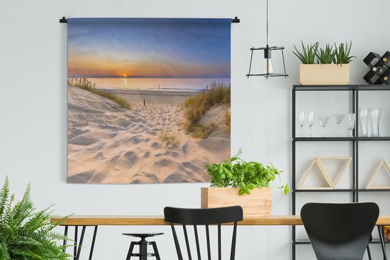 Wandkleed met zonsondergang op een strand met duinen en helmgras, hangend aan een zwarte roede in een eetkamer.
