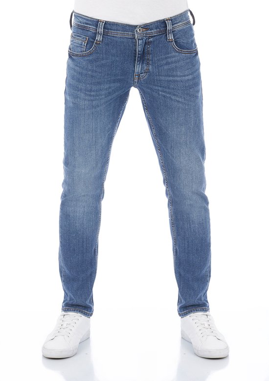 Man in blauwe tapered fit jeans en witte sneakers, van voren gezien.