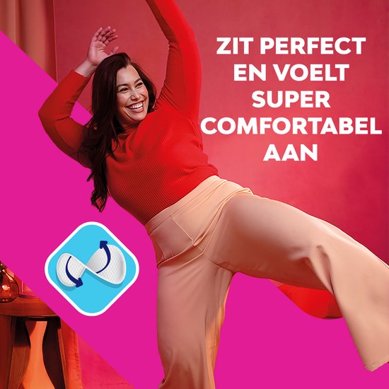 Vrolijke vrouw in rode top en beige broek, danst. Zit perfect en voelt super comfortabel aan.