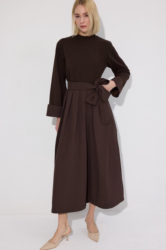 Donkerbruine jumpsuit met strikceintuur, wijde broekspijpen en opgestikte zakken.