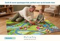 Opa en kind spelen met houten voertuigen op een zacht boerderijspeelkleed in een woonkamer.