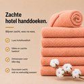 Stapel zalmroze handdoeken met takje katoen. Tekst: Zachte hotel handdoeken, luxe kwaliteit, dikke badstof.