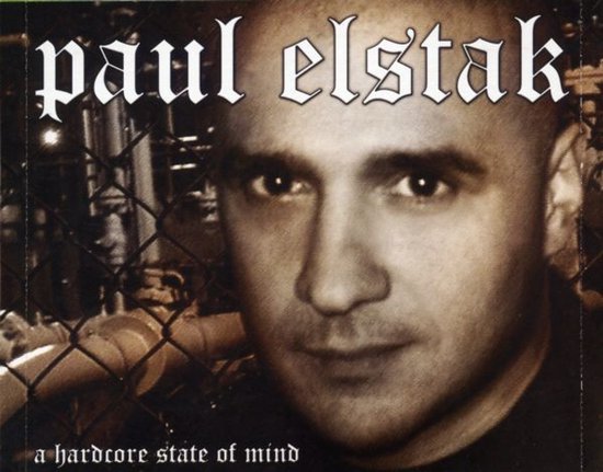 Portret van Paul Elstak voor een hek met de tekst 'a hardcore state of mind'.