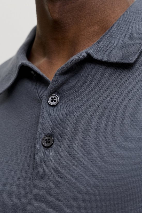 Close-up van de donkerblauwe gebreide polo met twee knopen.