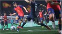 Spelers in Spaanse tenues nummer 20 die de bal dribbelen in een intens voetbalspel op een verlicht veld.