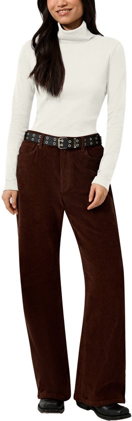 Model in witte coltrui, zwarte riem met oogjes en bruine ribfluwelen broek met wijde pijpen en zwarte laarzen.