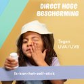 Meisje met zonnebrand stick 50 en witte zonnehoed beschermt haar ogen
