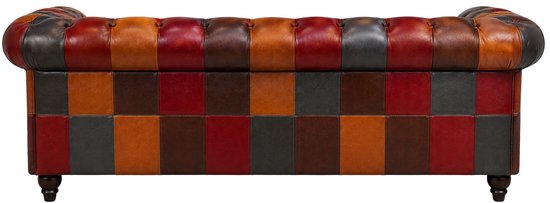 Een Chesterfield bank van leer met patchwork panelen in diverse kleuren rood, oranje, bruin en grijs.