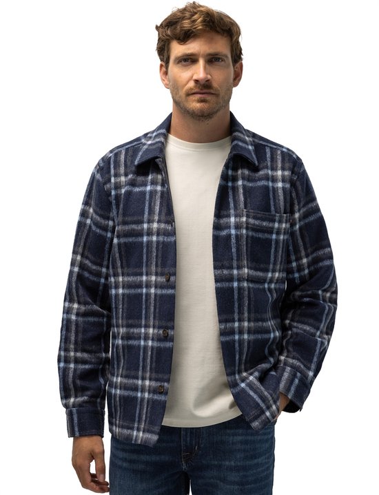 Man met donkerblauwe geruite jas van State of Art over een wit T-shirt.
