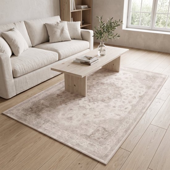 Beige crèmekleurig vloerkleed met medaillon-patroon in een lichte woonkamer, voor een bank.
