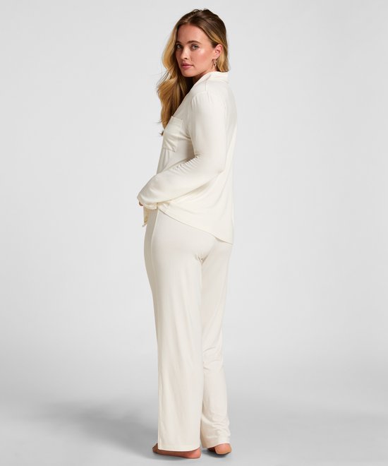 Model gezien vanaf de zijkant in een crèmewitte pyjamaset.