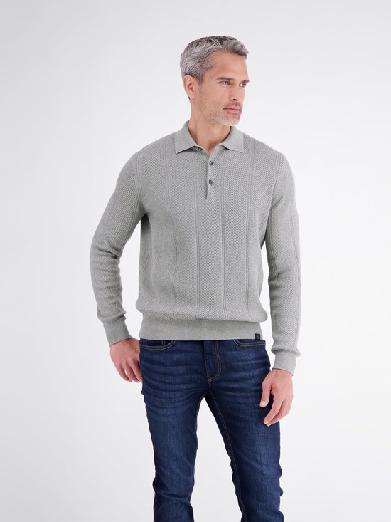 Model draagt een grijs poloshirt met lange mouwen, verticale strepen en een knoopsluiting, gecombineerd met blauwe jeans.