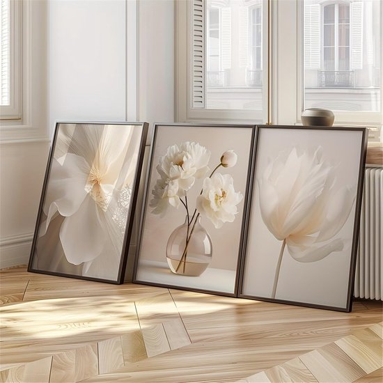 Drie ingelijste kunstwerken met witte bloemen op een houten vloer bij een raam.