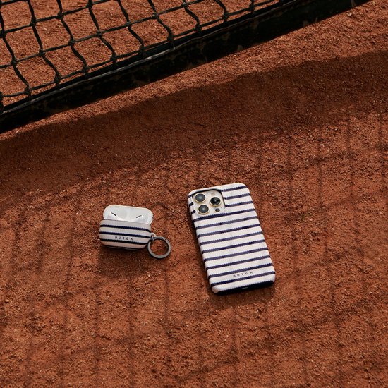 Marineblauw gestreept Burga iPhone hoesje en AirPods hoesje op een tennisbaan.