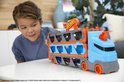Jongen kijkt naar blauwe en oranje Hot Wheels transporter. De transporter heeft twee verdiepingen voor auto's.