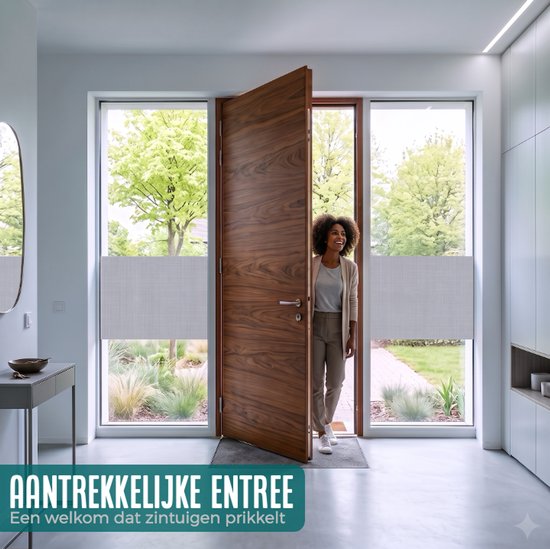 Vrouw in entree van een modern huis, kijkend naar buiten door een open houten deur met grijze raamfolie.