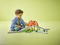 Kind speelt met LEGO Duplo treinbaan, met oranje bruggen, groene steunen en een stationnetje.