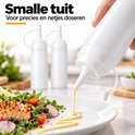 Hand die een witte knijpfles gebruikt om gele saus precies over een gerecht met zalm te doseren.