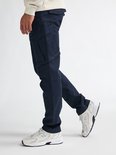 Model draagt een marineblauwe Petrol Industries cargobroek met zijzakken en lichte sneakers.