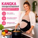 Zwangere vrouw in beige jurk met zwarte zwangerschapsband kookt in de keuken.