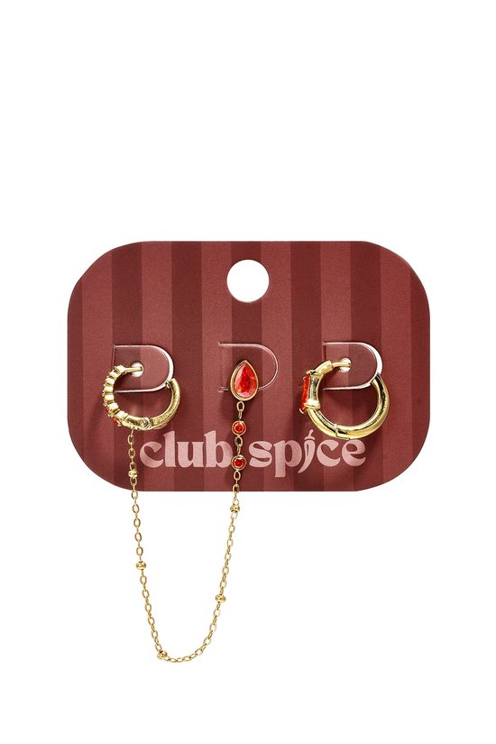 Set oorbellen van Club Spice op een bordeauxrode kaart, met rode steentjes, bungelende ketting en gouden ringetjes.
