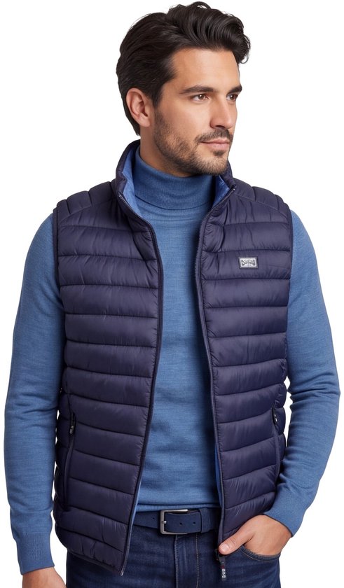 Model draagt een donkerblauwe, gewatteerde N.Z.A. bodywarmer met logo over een blauwe coltrui.