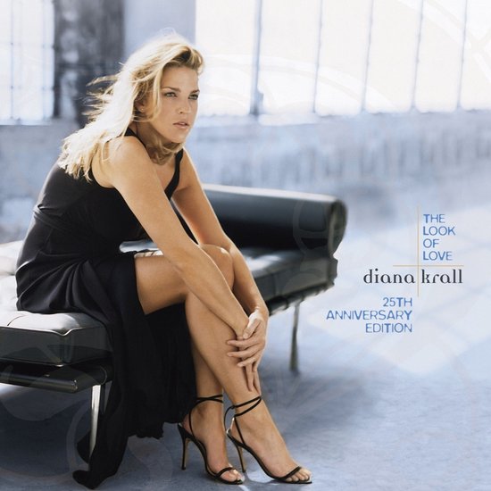 Diana Krall in een zwarte jurk en hakken zittend op een bank, albumhoes 'The Look Of Love 25th Anniversary Edition'.