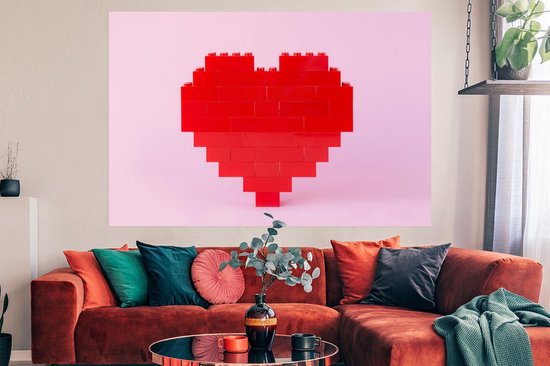 Rood hart van bouwblokken op een roze achtergrond, boven een rode bank in een woonkamer.