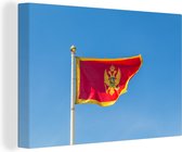 Canvas Schilderij Vlag van Montenegro afgebeeld tegen een heldere blauwe hemel - 120x80 cm - Wanddecoratie