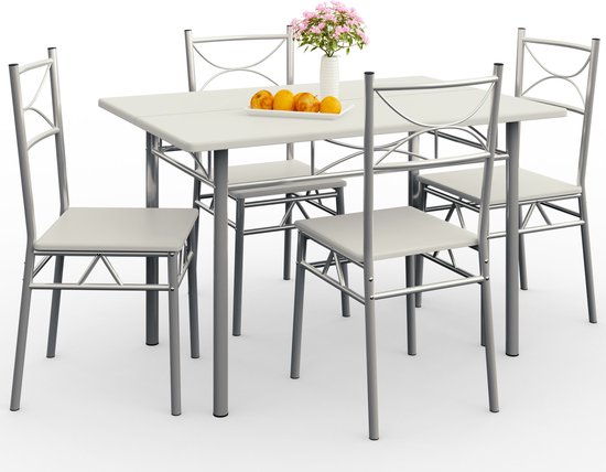 Wit eettafel met vier stoelen, vaas met roze bloemen en een schaal met sinaasappels.